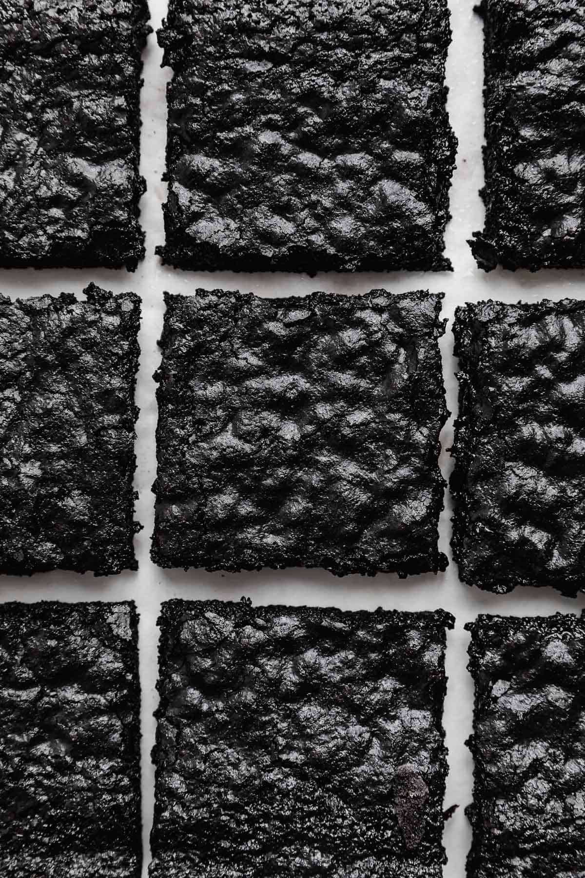 Overhead photo of Black Cocoa Brownies cut into squares with only a small space between each brownie, on a white background.