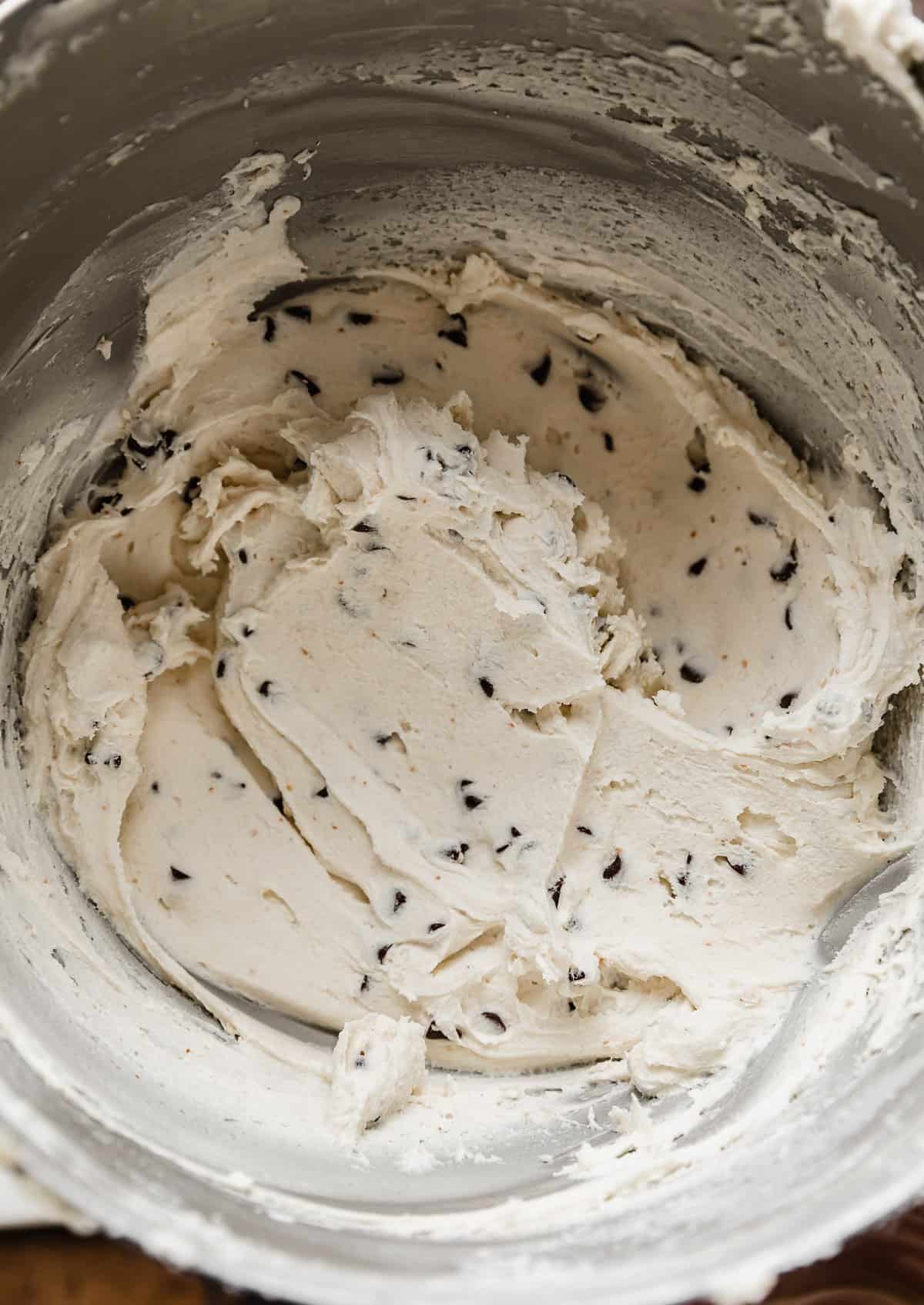Close up photo of white frosting that has mini chocolate chips mixed into it.