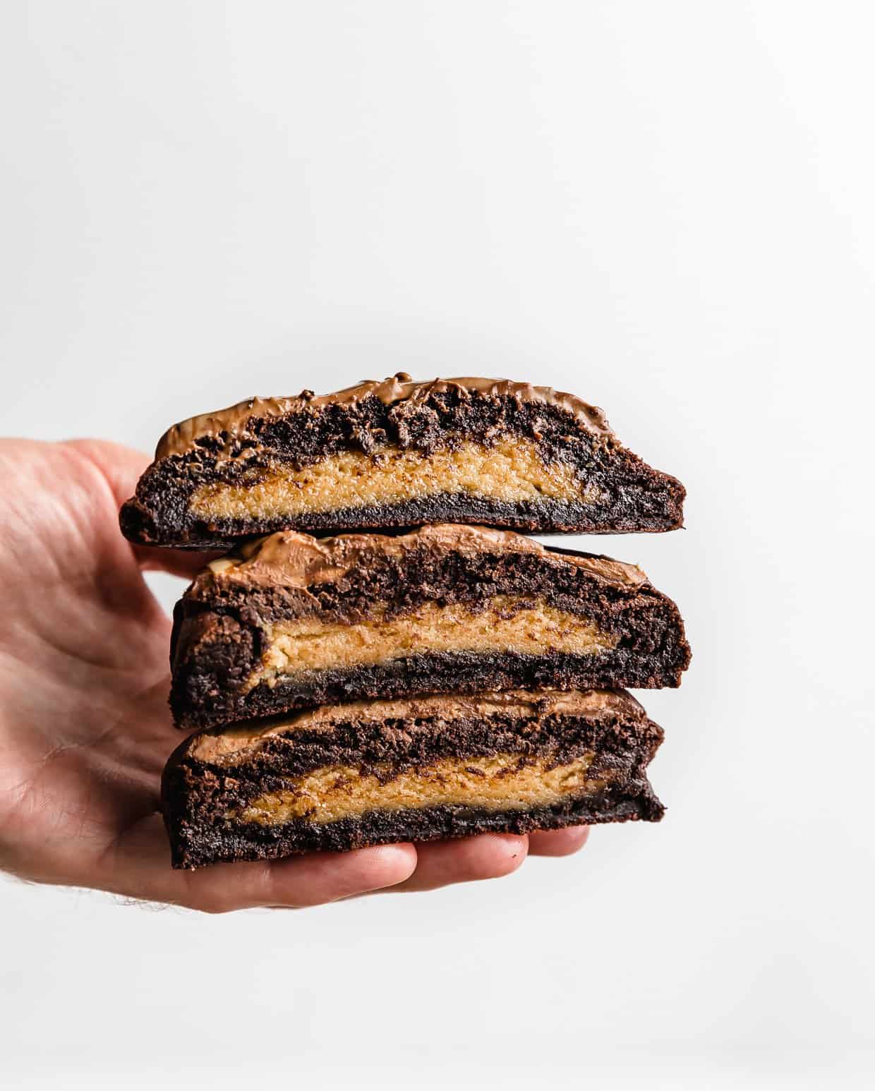 A hand holding Peanut Butter Brownie Cookies against a white background.