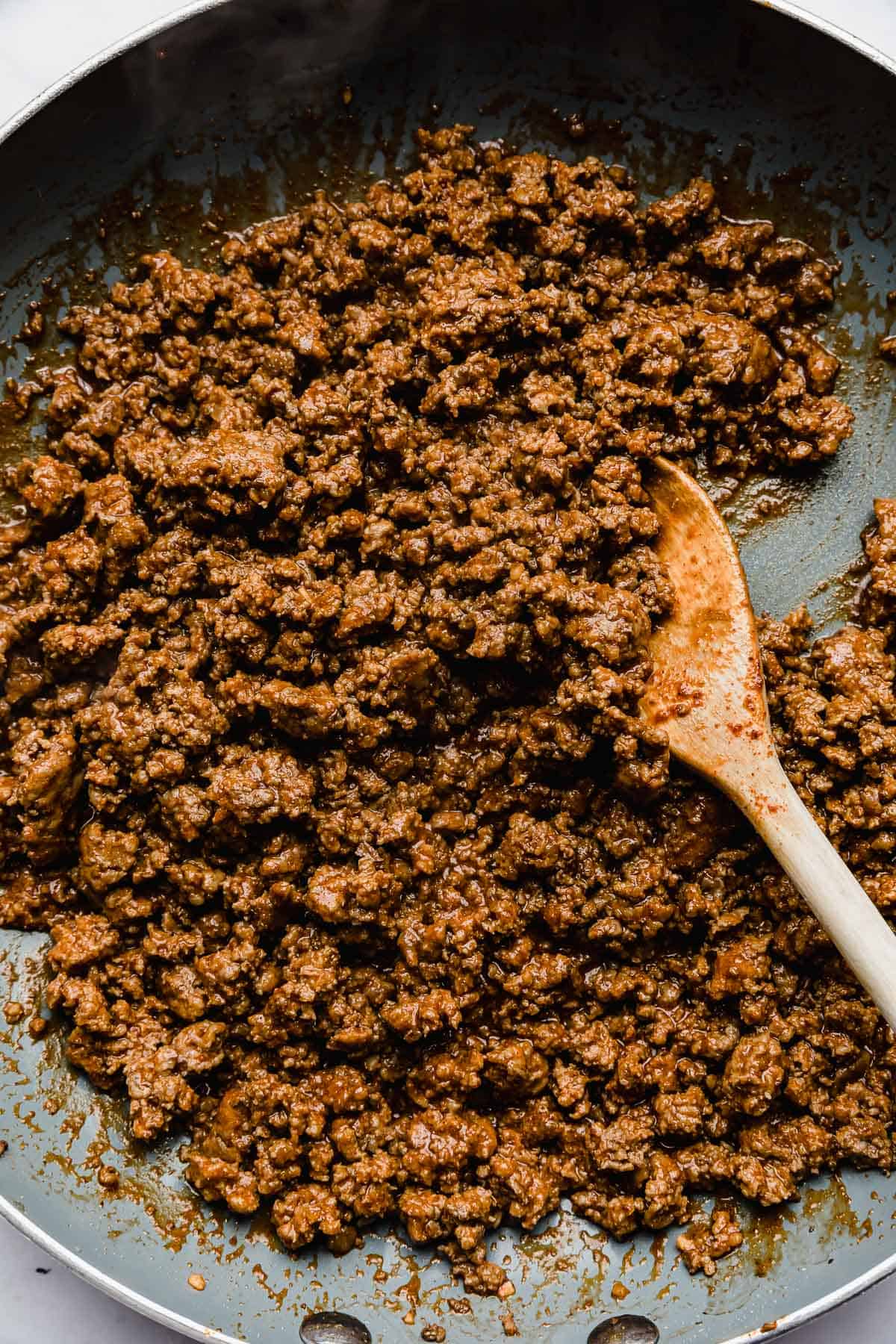 Ground beef mixed with taco seasoning in a grey skillet.