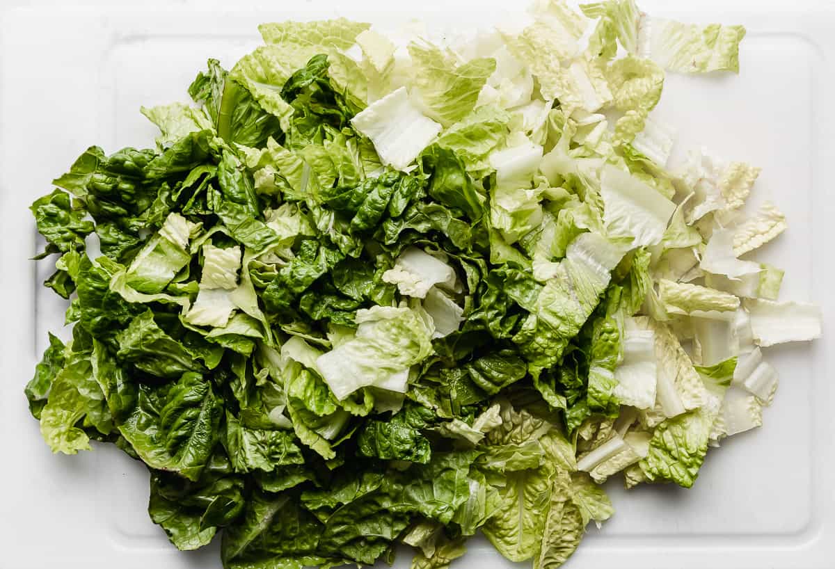 Chopped romaine lettuce on a white cutting board.