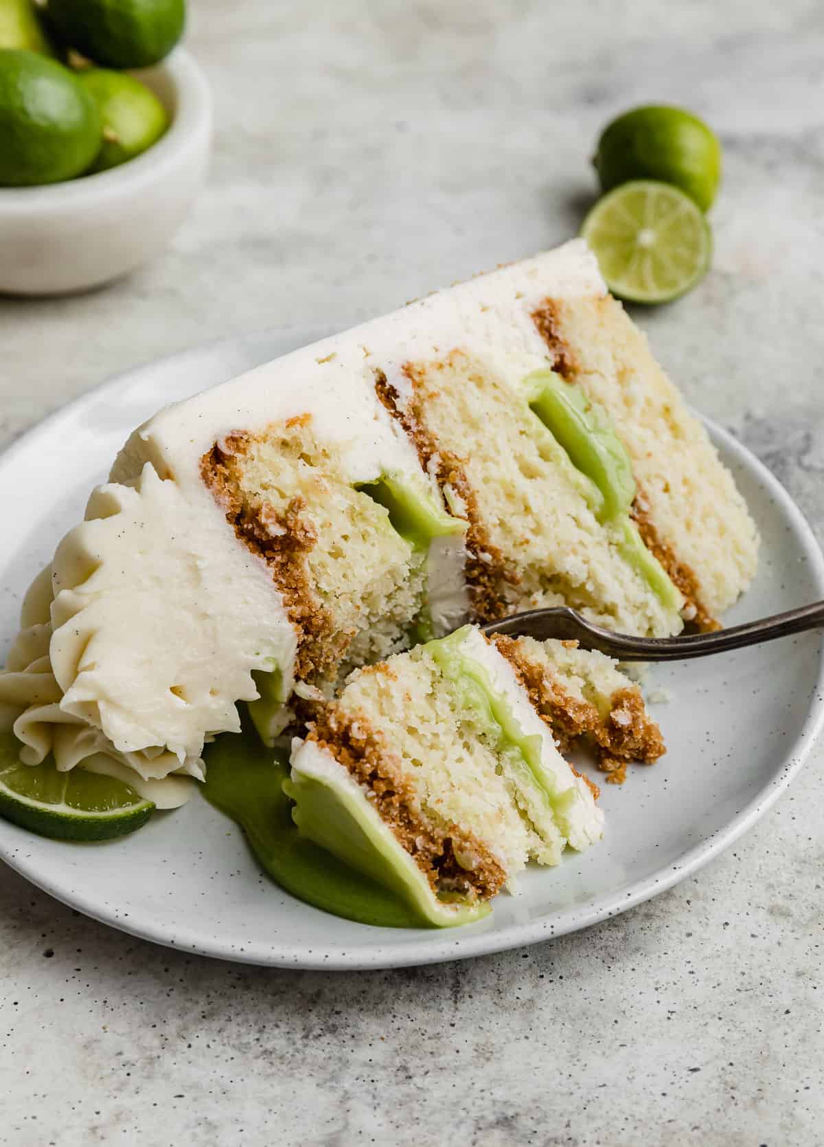 A three cake layered Key Lime Cake slice on a white plate.