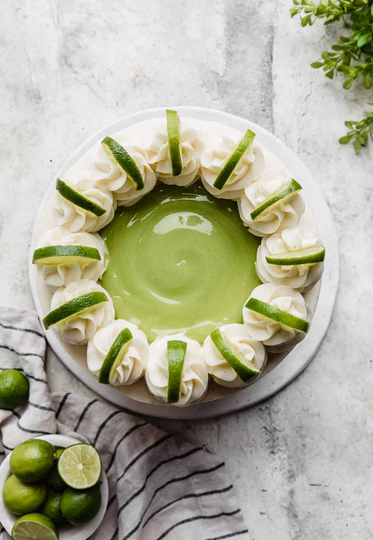 Overhead photo of a Key Lime Cake topped with lime curd, frosting swirls and lime slices on each swirl.