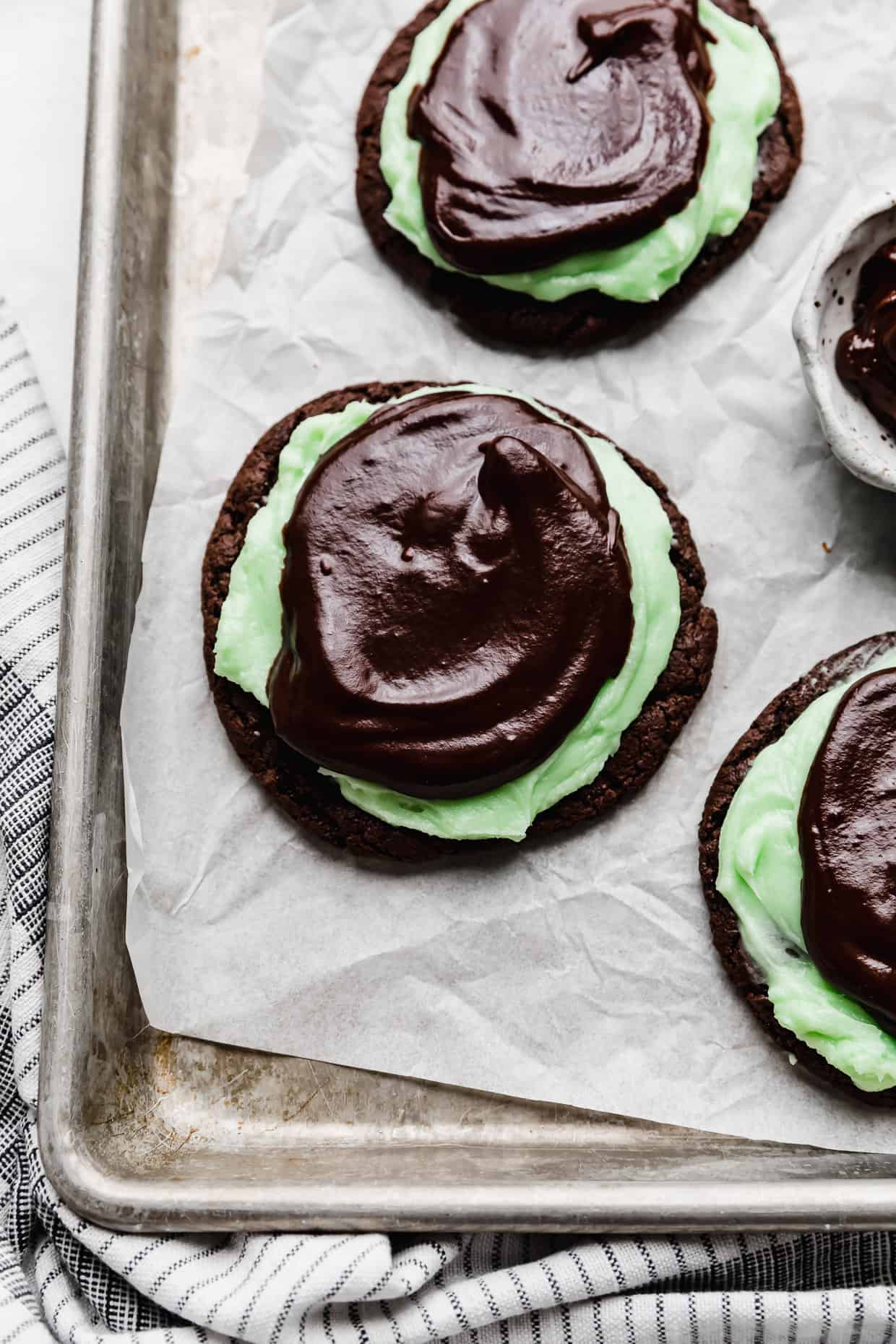 Copycat Crumbl Mint Brownie Cookies on a parchment paper that's on a baking sheet.