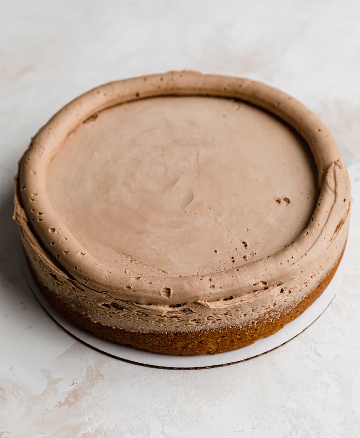 A butterscotch chocolate frosting rim piped around the edges of a round cake layer.