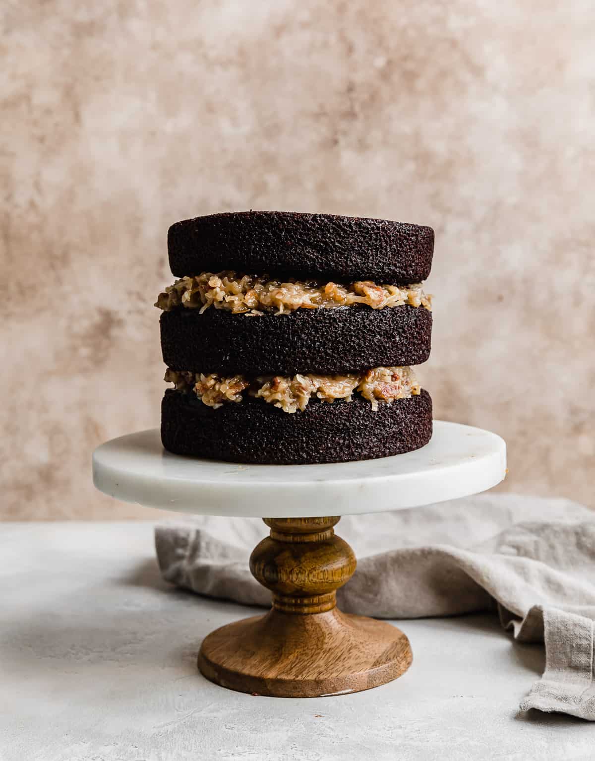 A three tier German chocolate cake with coconut pecan frosting between each layer.