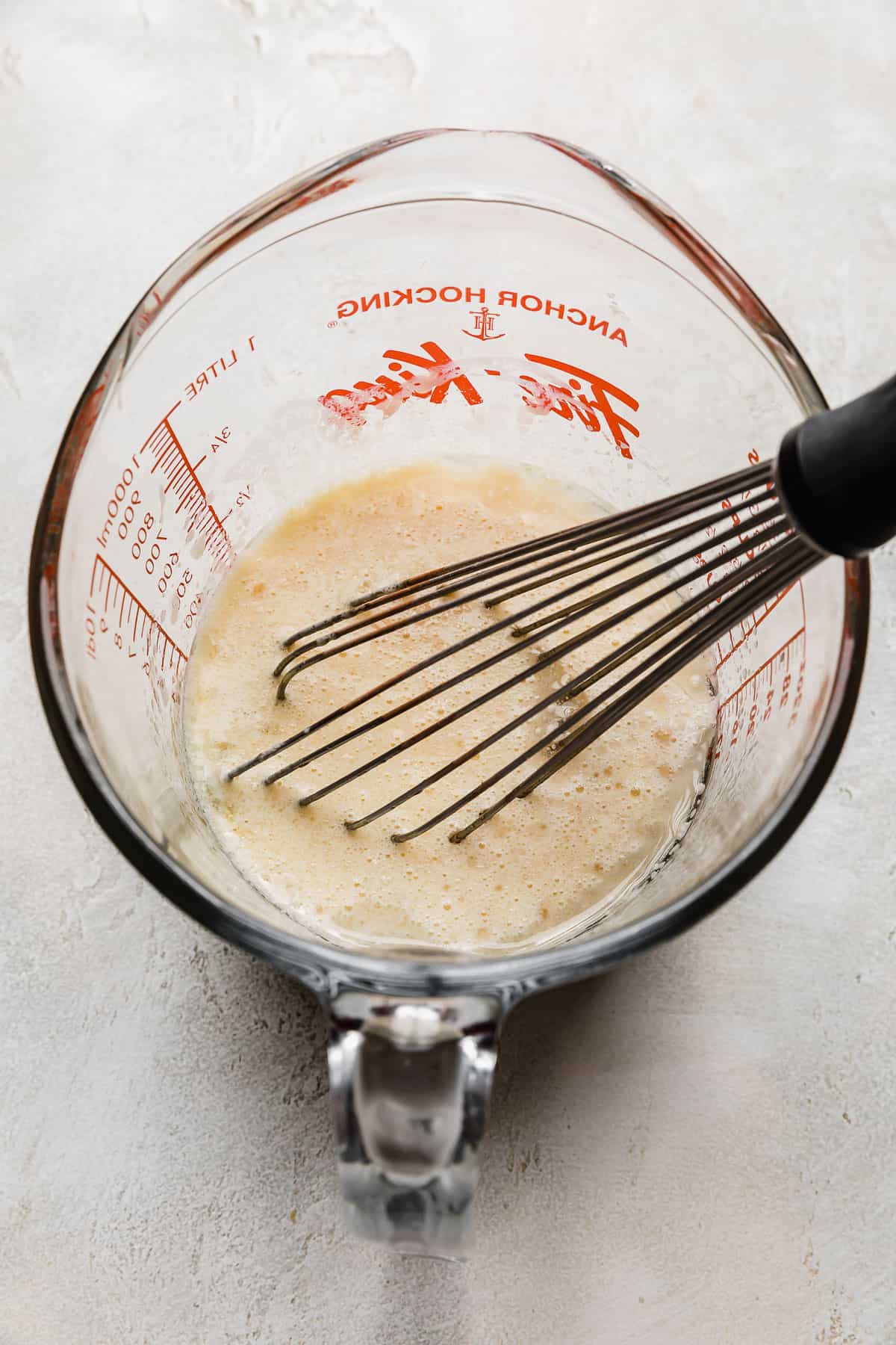 A light yellow colored liquid in a liquid measuring cup used for making a 6 inch German Chocolate Cake.