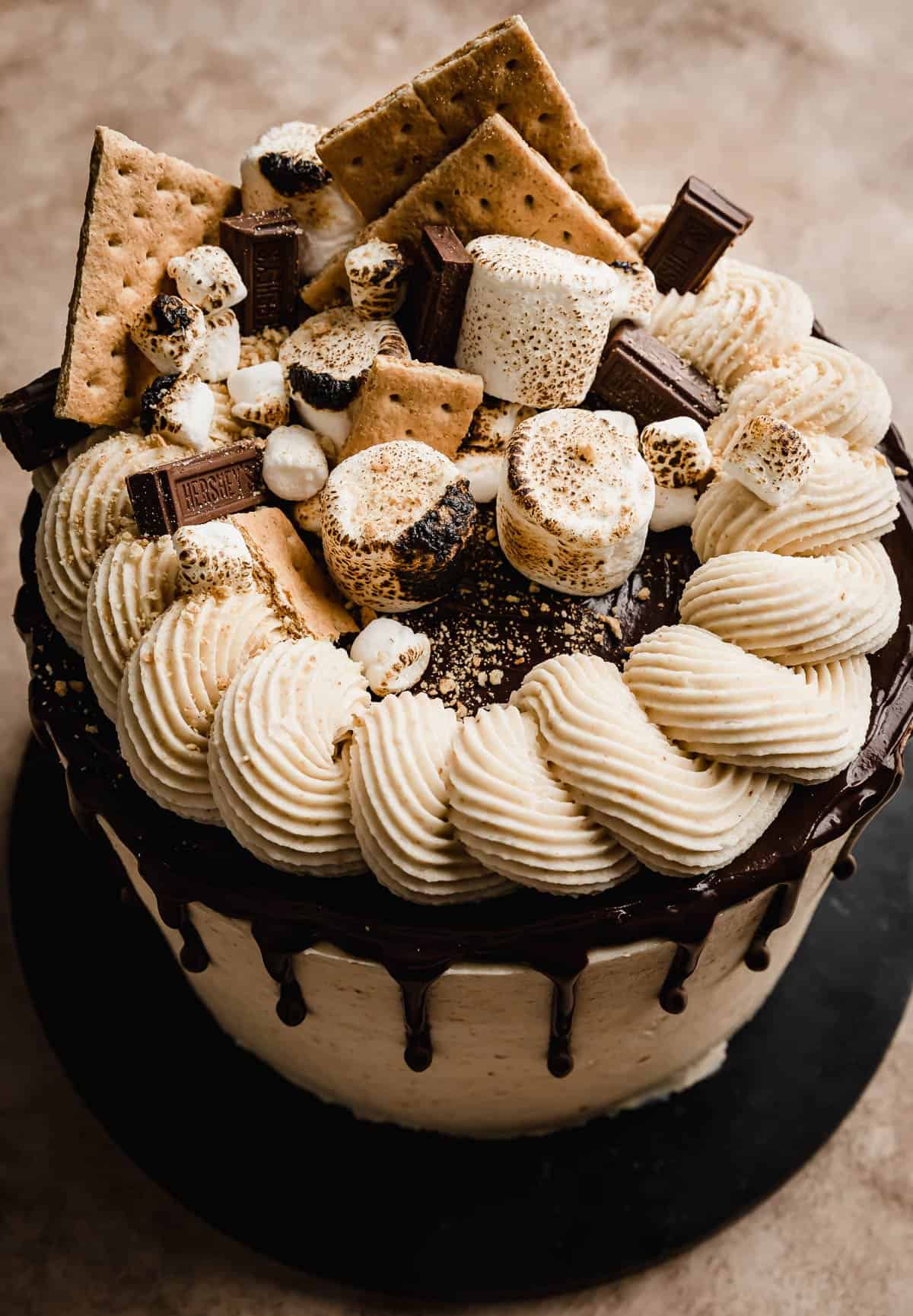 The top of a S'mores layer cake decorated with graham crackers, toasted mini and large marshmallows, and chocolate squares. 
