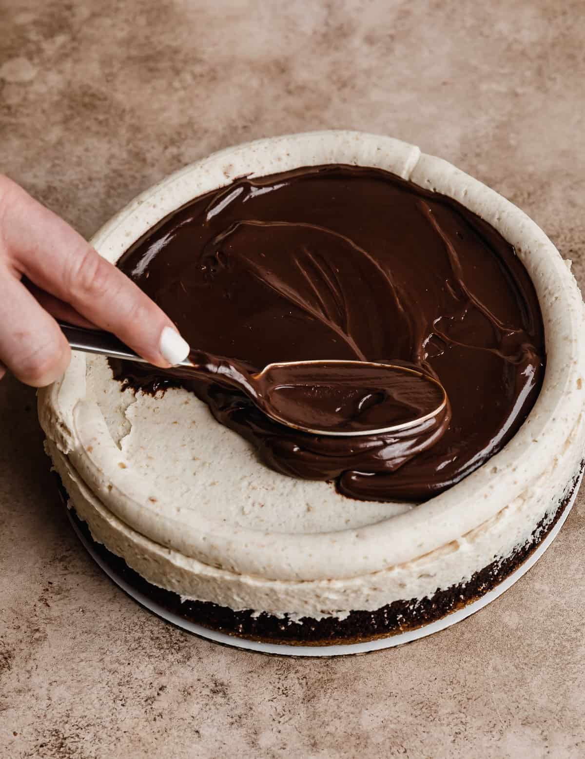 Chocolate ganache filling being spread overtop a frosted S'mores Cake layer.