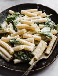 A black plate with creamy Boursin Pasta tossed with spinach.