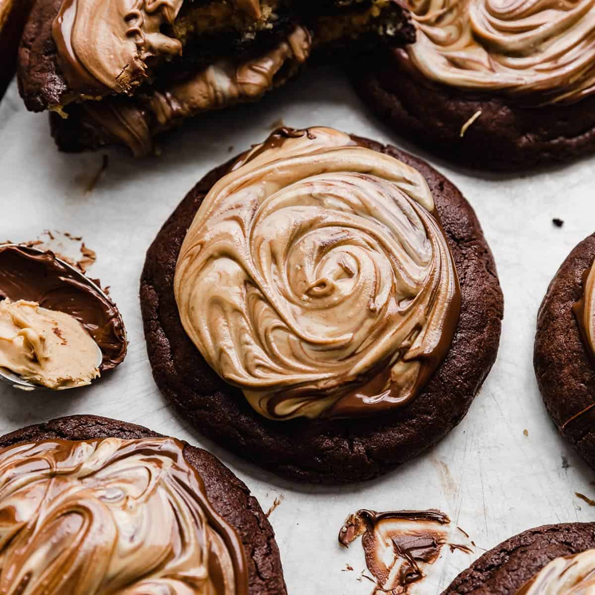 A brownie cookie topped with melted chocolate and peanut butter that has been swirled together.