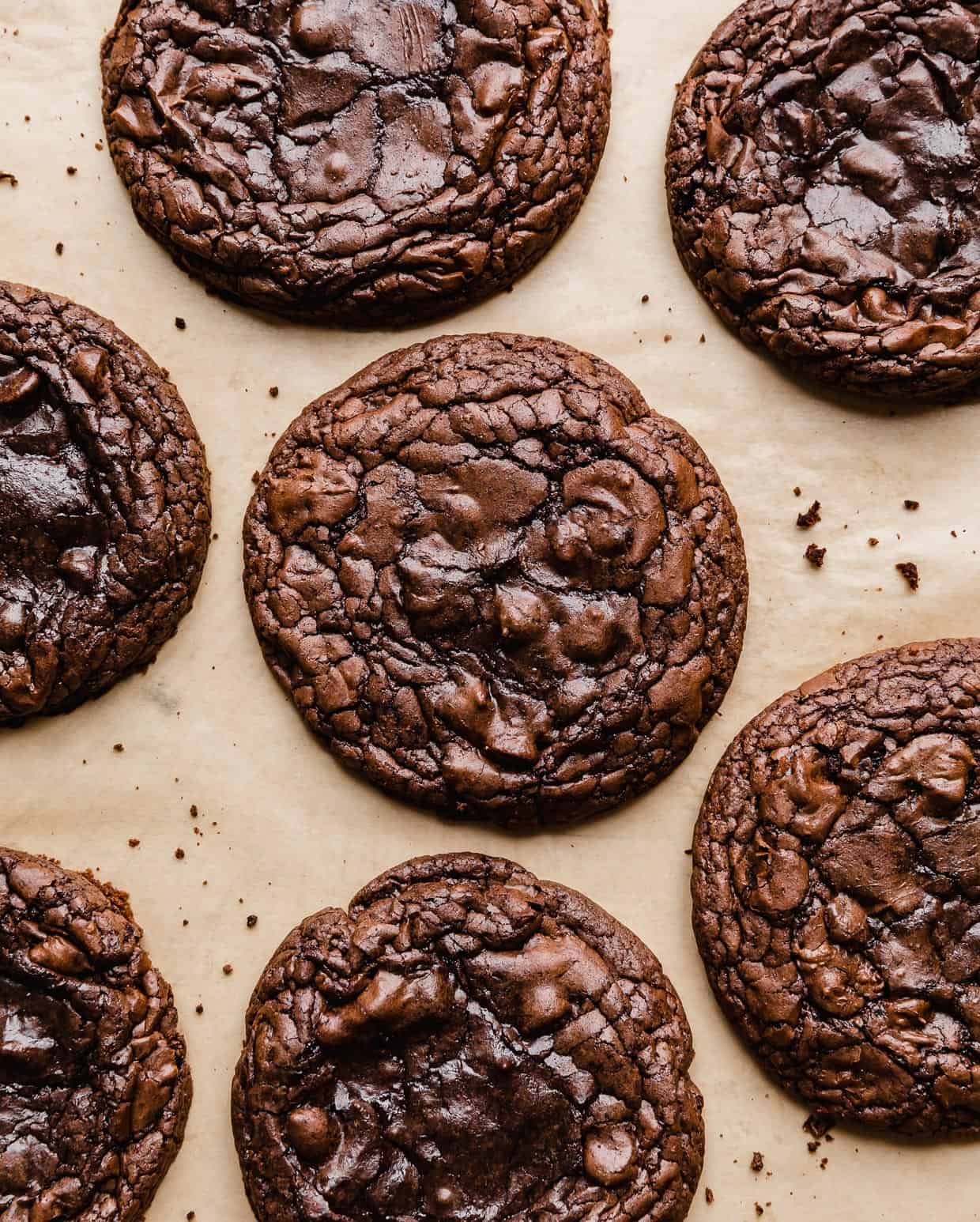 Crumbl Brownie Batter Cookies with crackly tops on a tan parchment paper.