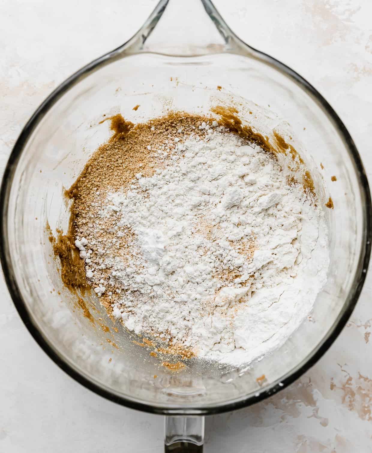 Graham cracker crumbs and flour in a glass mixing bowl.