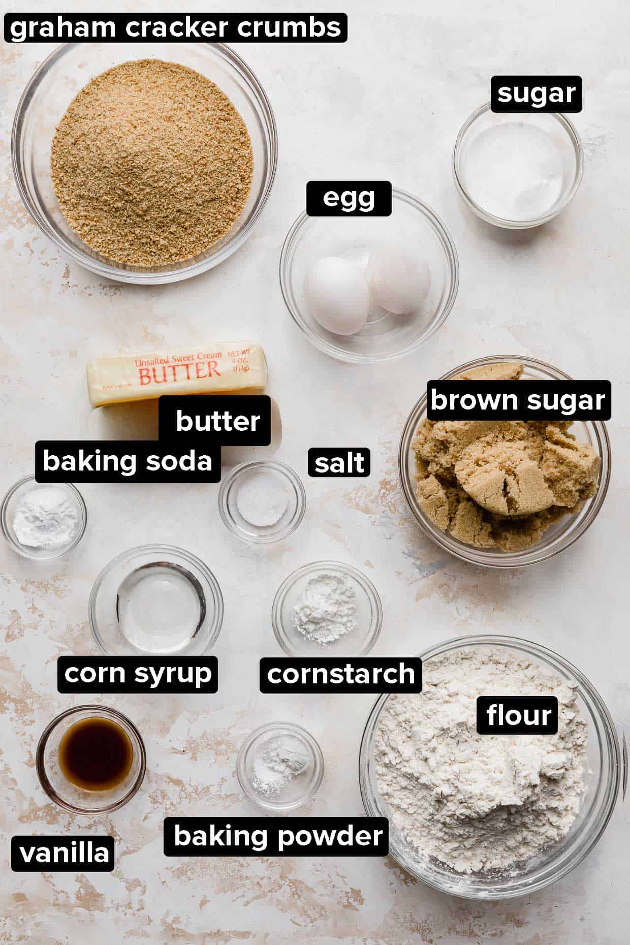 Ingredients used to make New York Cheesecake cookies portioned into glass bowls on a white background.