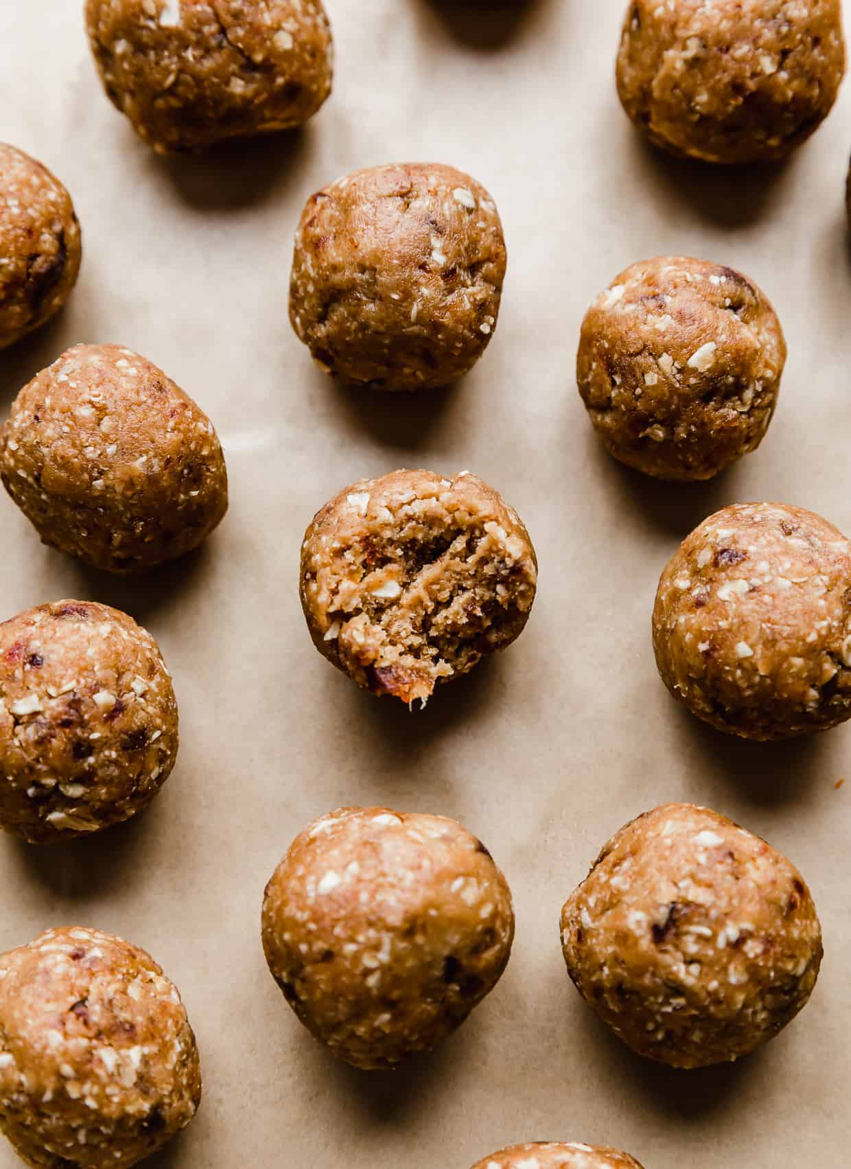 A bite taken out of a Peanut Butter Bliss Ball that is surrounded by other small bliss balls.