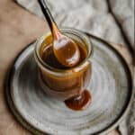 Salted Butterscotch Sauce in a jar on a gray plate.