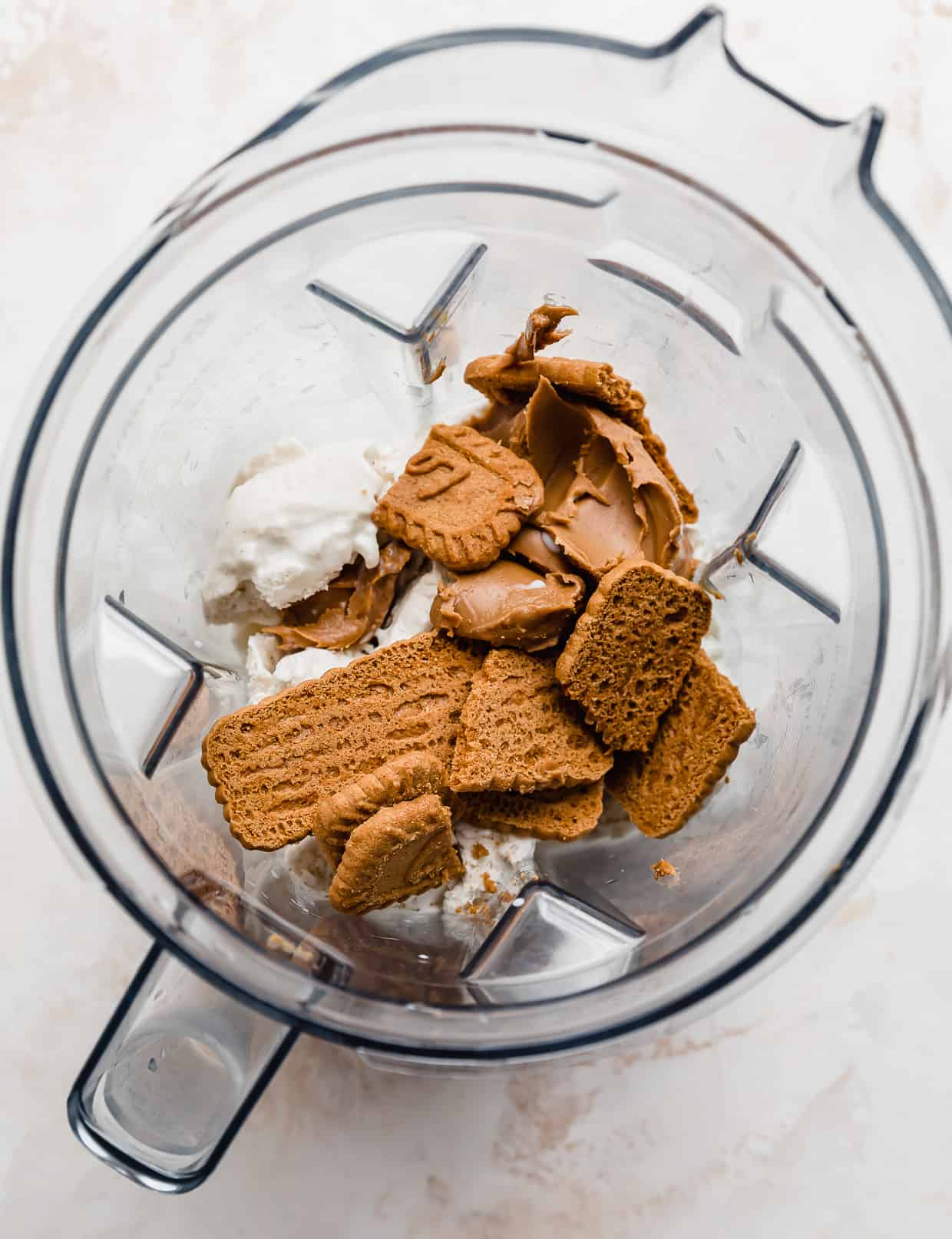 A blender filled with vanilla ice cream, cookie butter, and biscoff cookies.