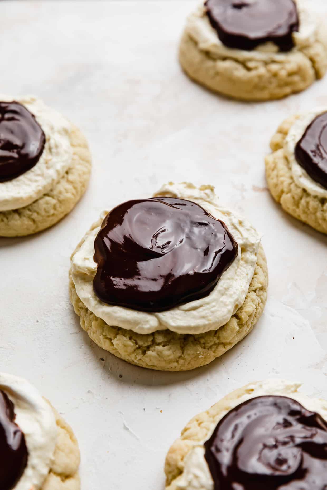 Crumbl Boston Cream Pie Cookies with a chocolate ganache on top of the cream covered cookies.