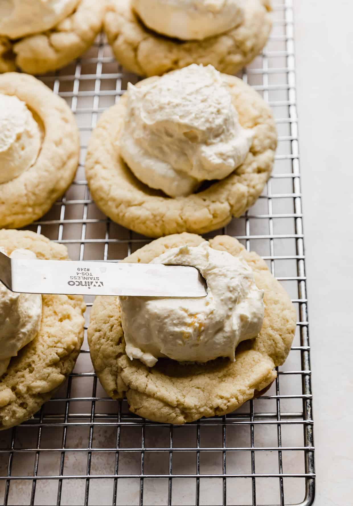 An offset spatula spreading cheaters pastry cream on a cookie.