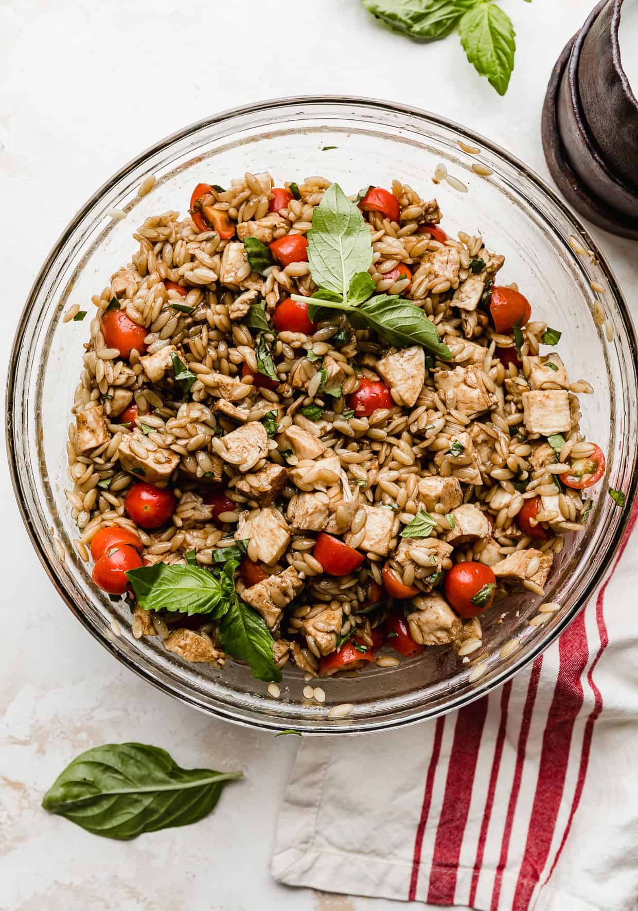 A chicken Caprese Orzo Salad in a glass bowl with a balsamic dressing.