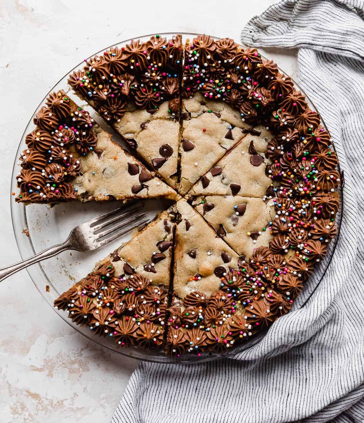 A Chocolate Chip Cookie Cake Recipe made in a pie plate with the cookie cake cut into wedges.