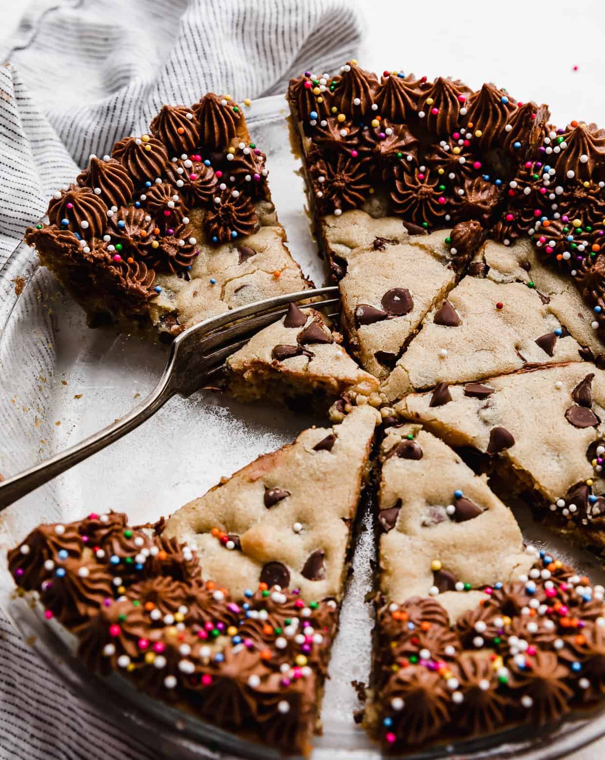 A fork cutting into a wedge slice of the best Chocolate Chip Cookie Cake Recipe.
