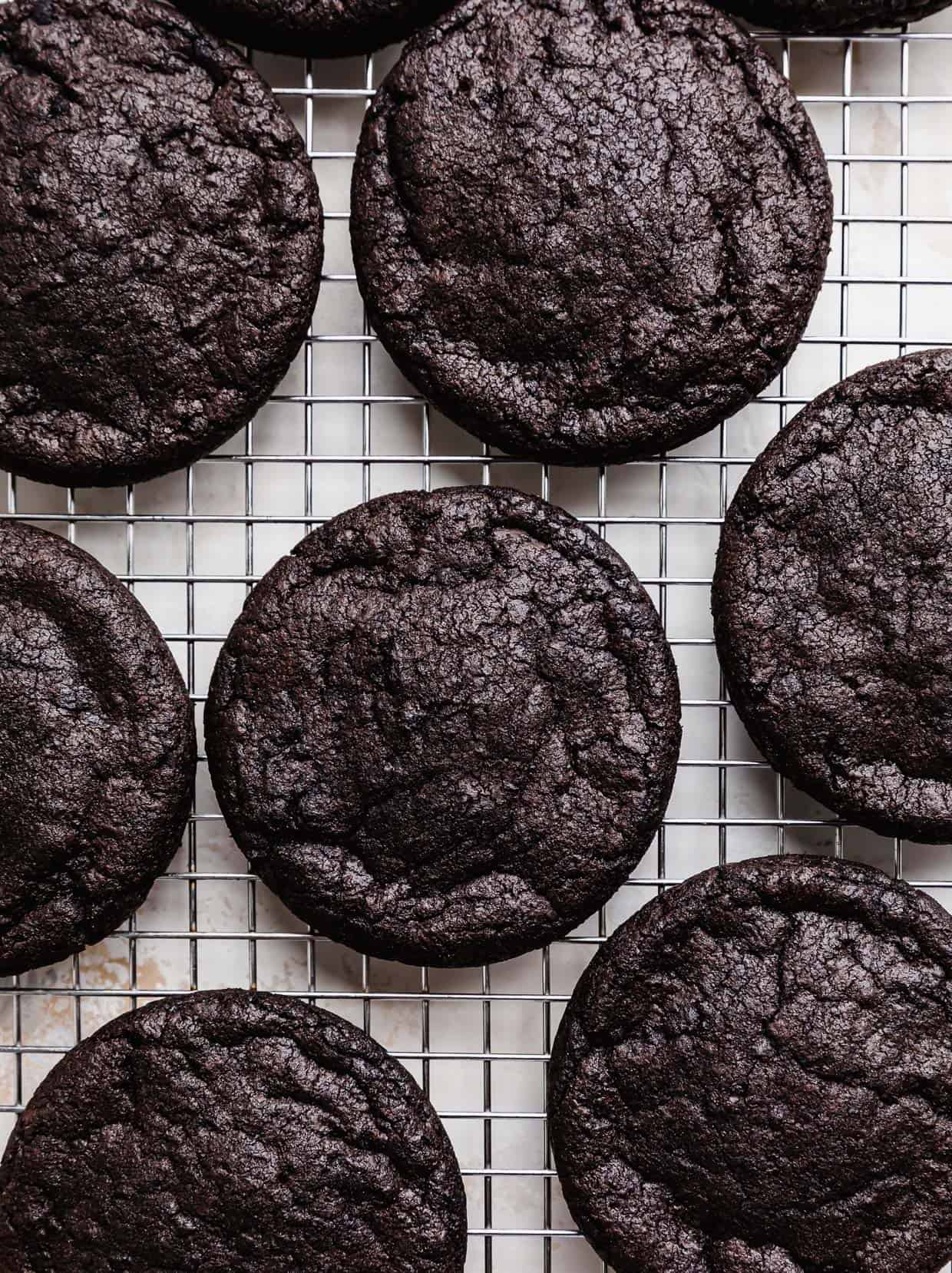 Baked dark Oreo cookies on a wire cooling rack.