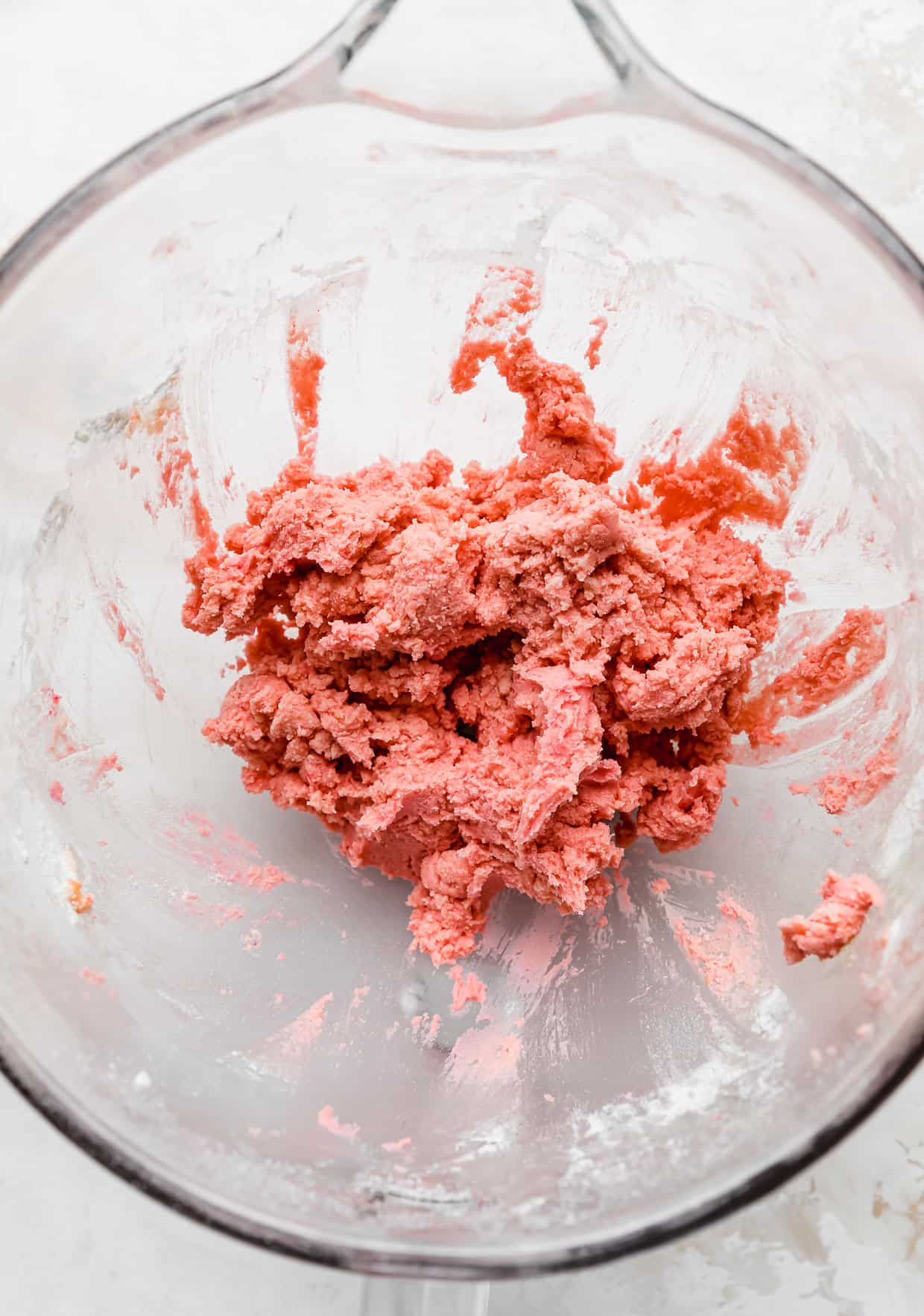 Pink Velvet Cookie dough in a glass bowl on a white background.