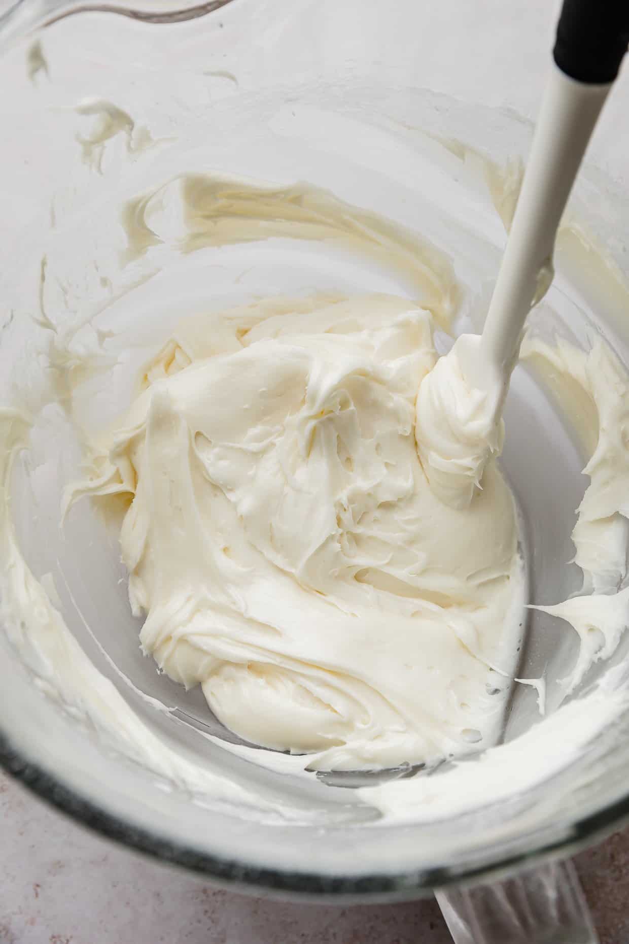 A white caramel cream cheese frosting in a glass bowl.