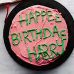 Hagrid cake that was made for Harry Potters Birthday, pink frosting and green lettering on a black plate.