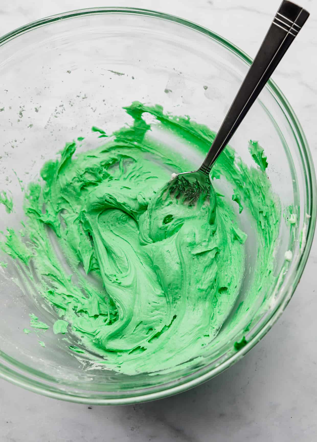 Bright green frosting in a glass bowl.