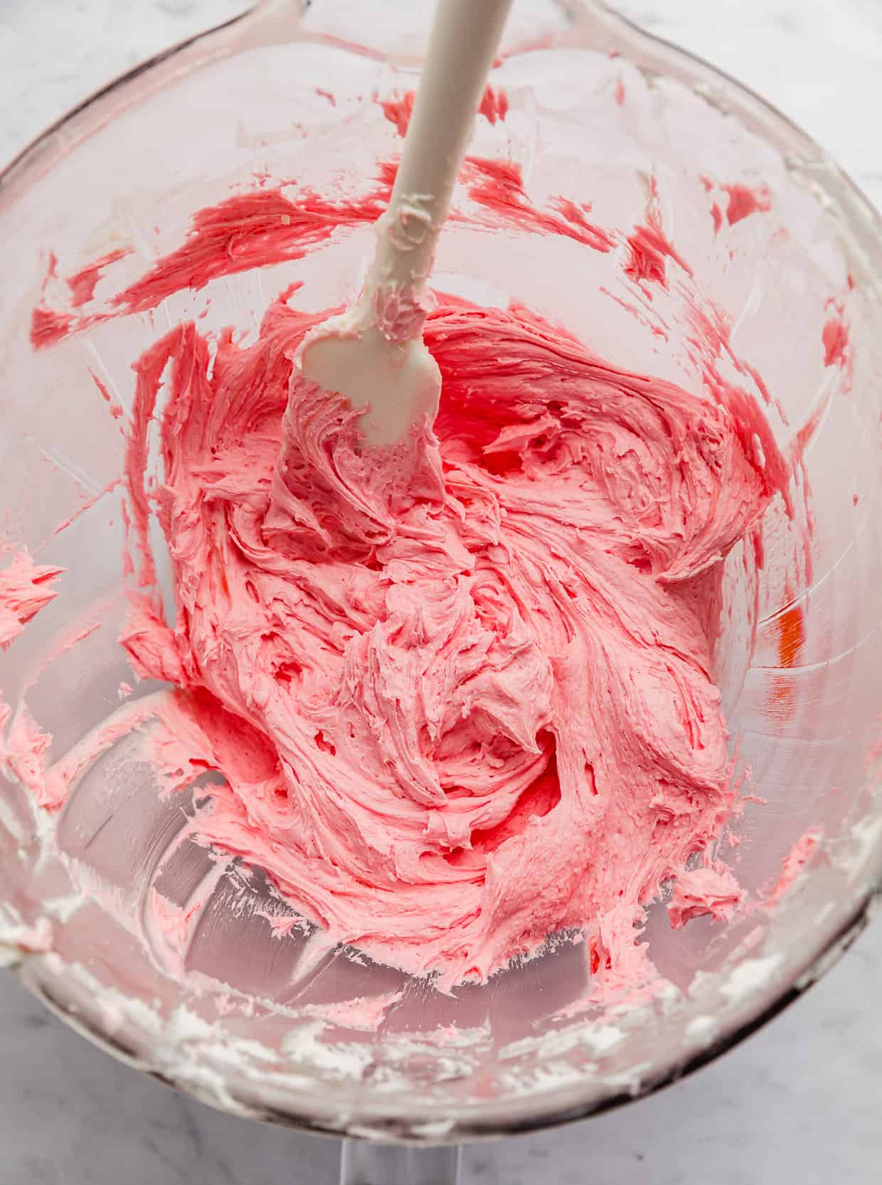 Pink frosting in a glass bowl.