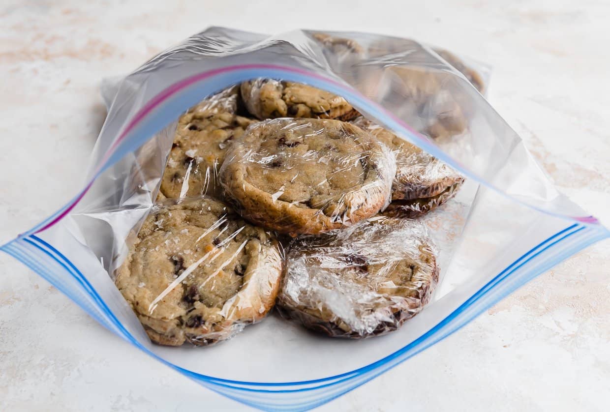 A ziplock bag with chocolate chip cookies individually wrapped in plastic wrap.
