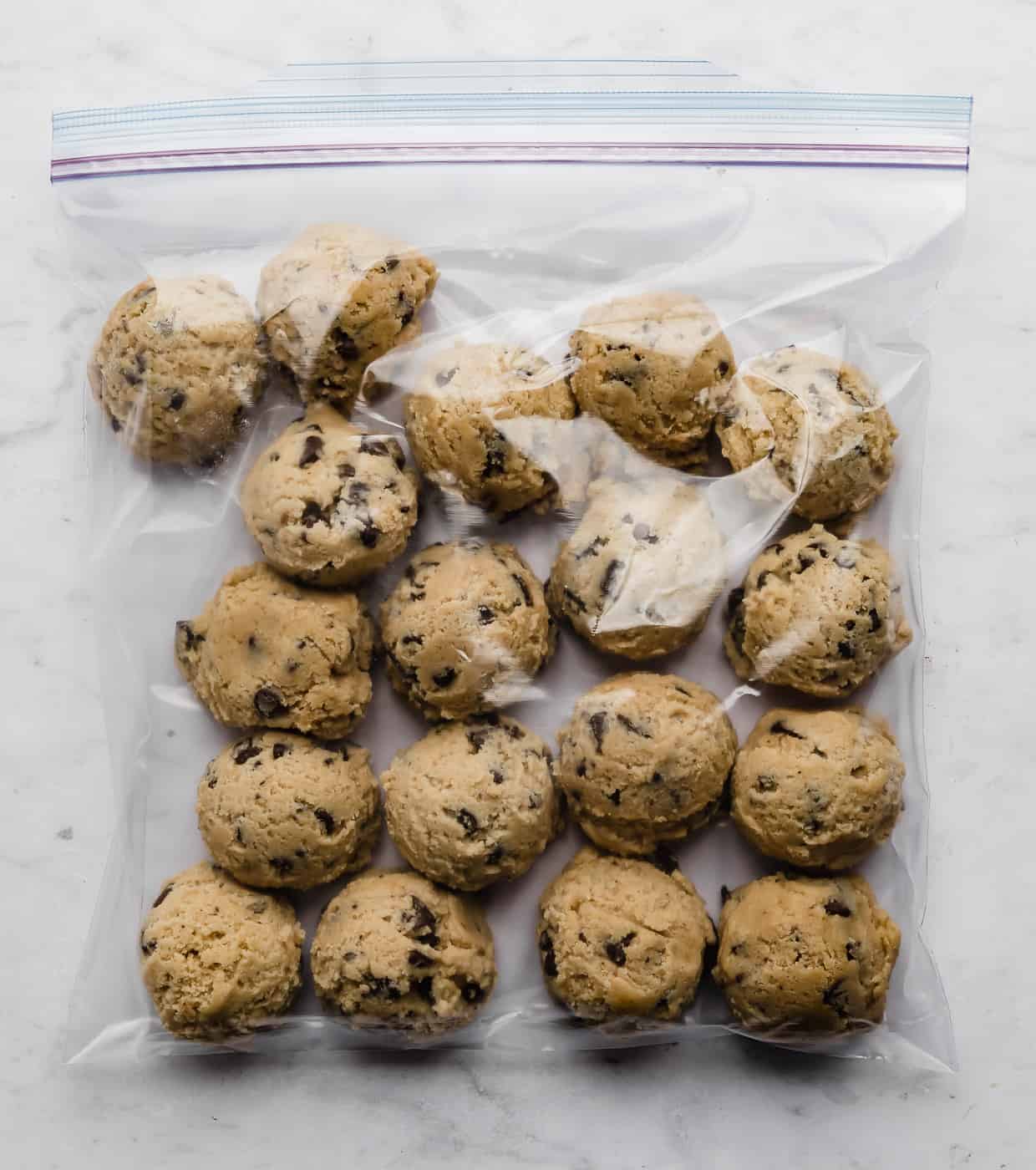 Chocolate chip cookie dough balls in a ziplock bag on a white background.