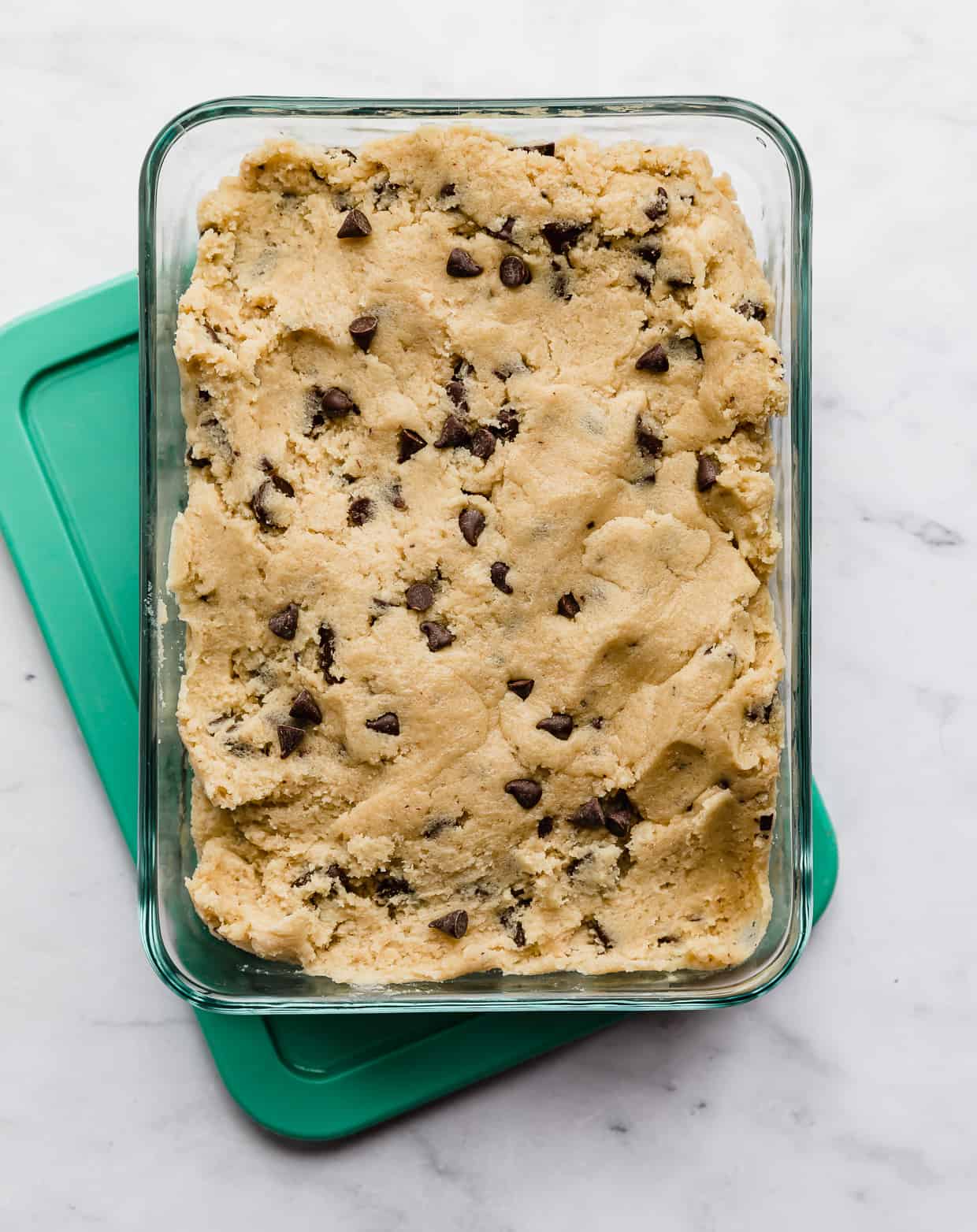 Chocolate chip cookie dough in a rectangle glass storage container.