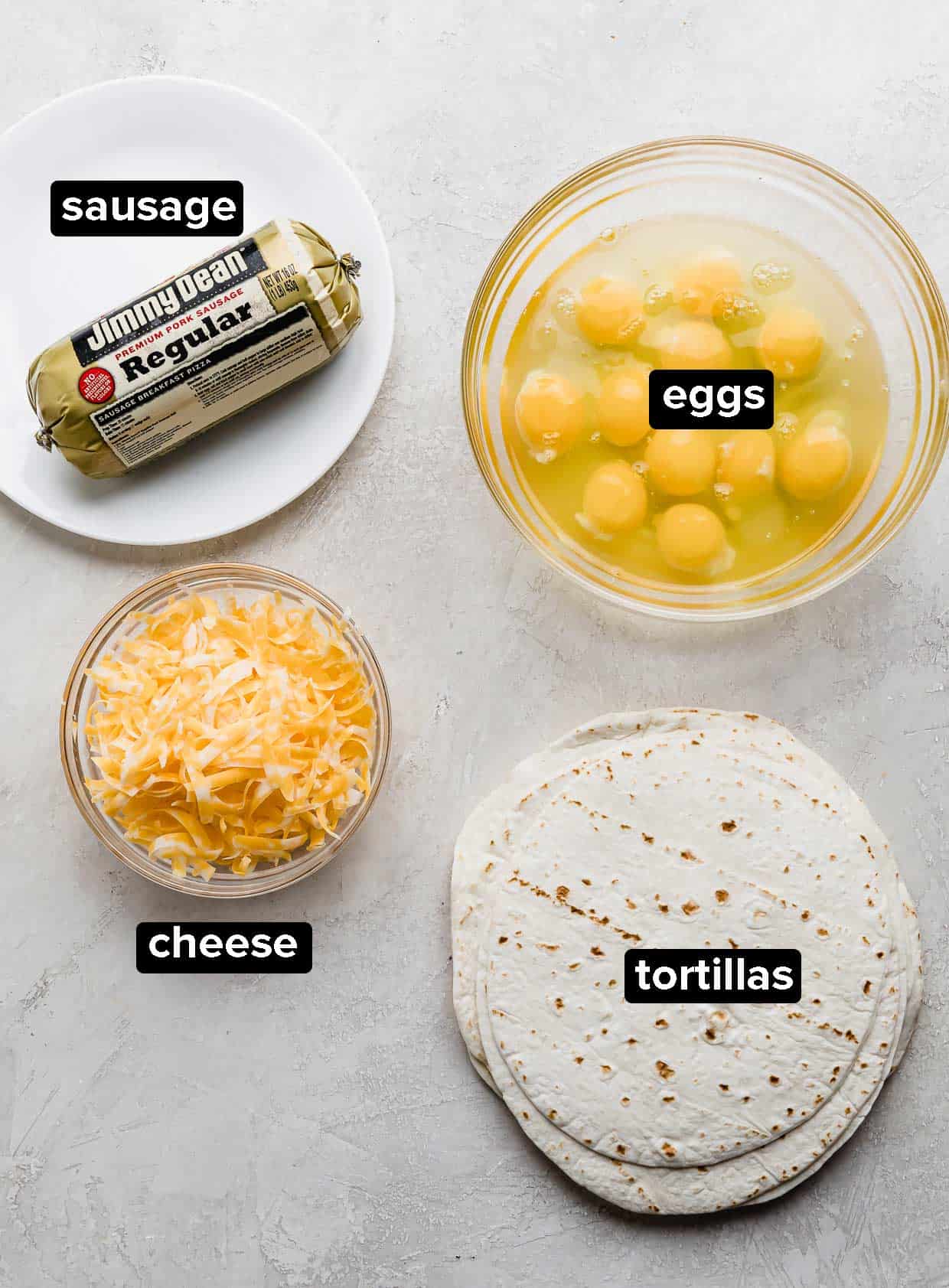 Jimmy Dean sausage, bowl of eggs, cheese, and tortillas on a gray background.