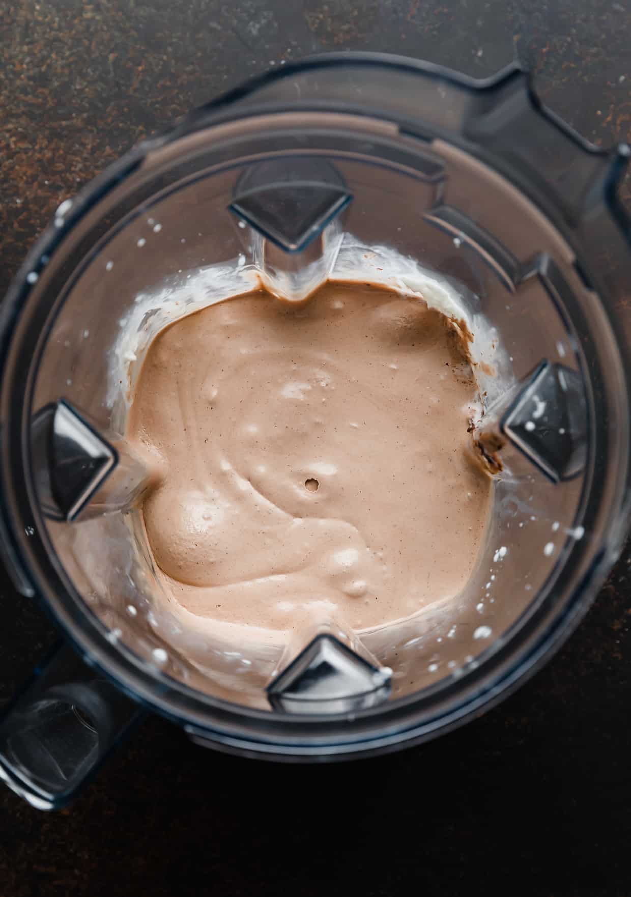 A light brown Nutella Milkshake blended, in a blender.