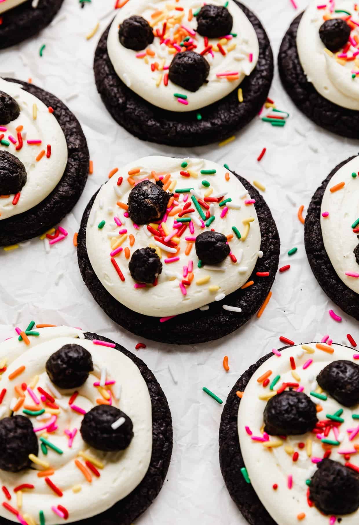 Oreo Birthday Cake Cookies topped with a white frosting, colored sprinkles and small Oreo truffles.