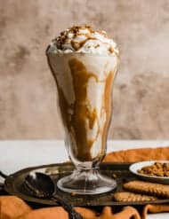 A lotus Biscoff shake in a glass cup topped with whipped cream and crushed Biscoff cookies.