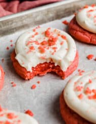 A Pink Velvet Cookie topped with frosting and pink cookie crumbs.