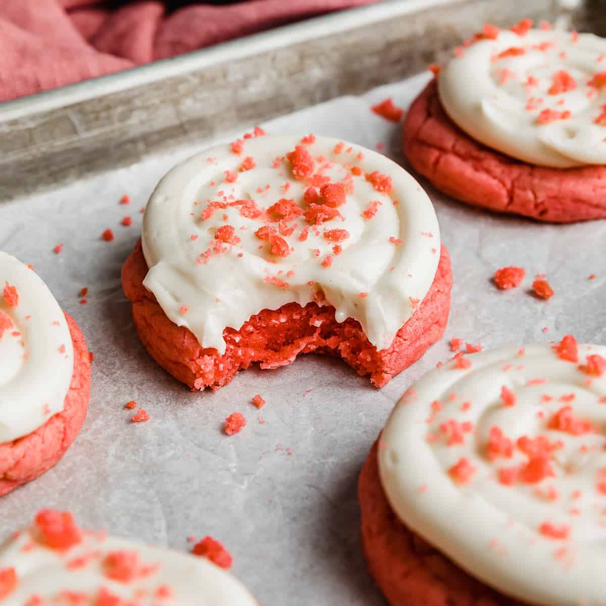A Pink Velvet Cookie topped with frosting and pink cookie crumbs.