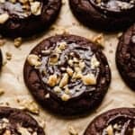 A chocolate brownie cookie topped with a melted chocolate ganache and chopped walnuts.