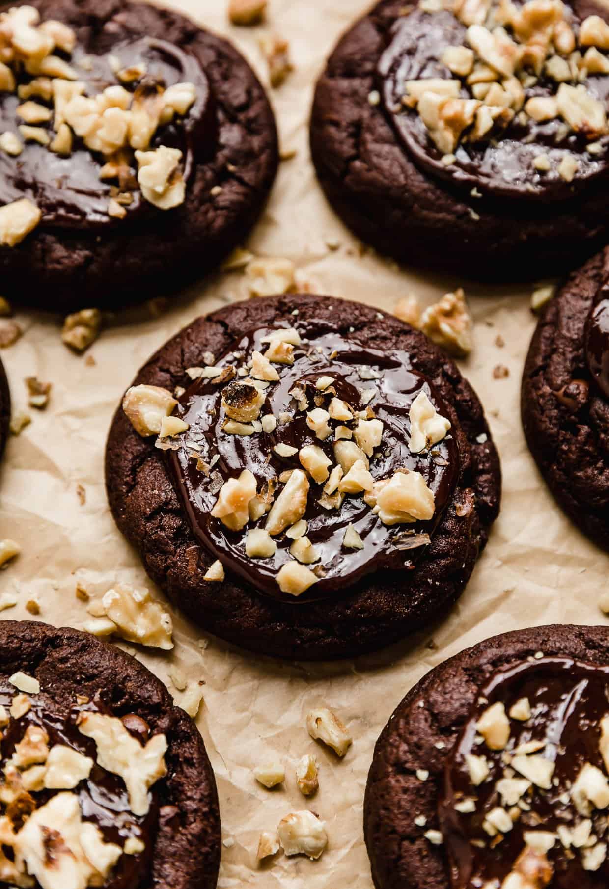 A chocolate brownie cookie topped with a melted chocolate ganache and chopped walnuts.