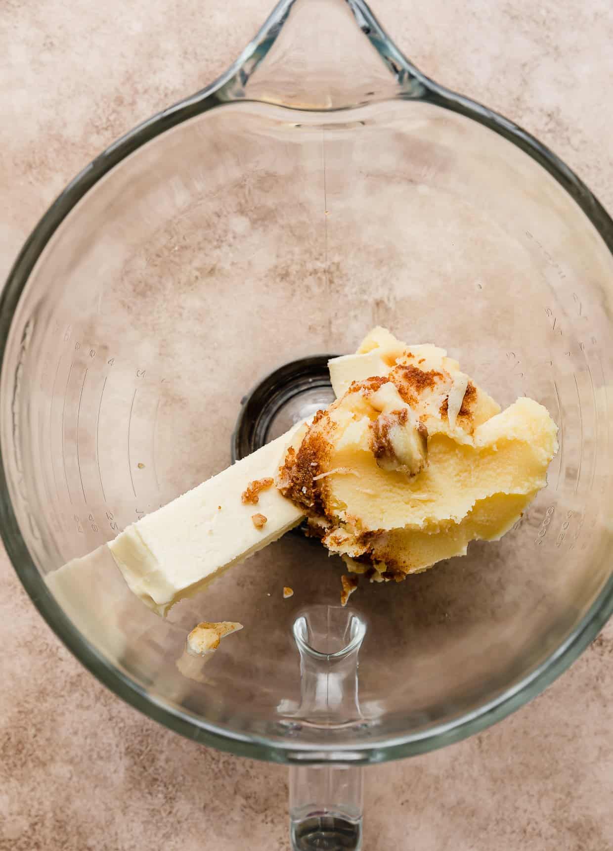 Brown butter and a stick of butter in a glass bowl.