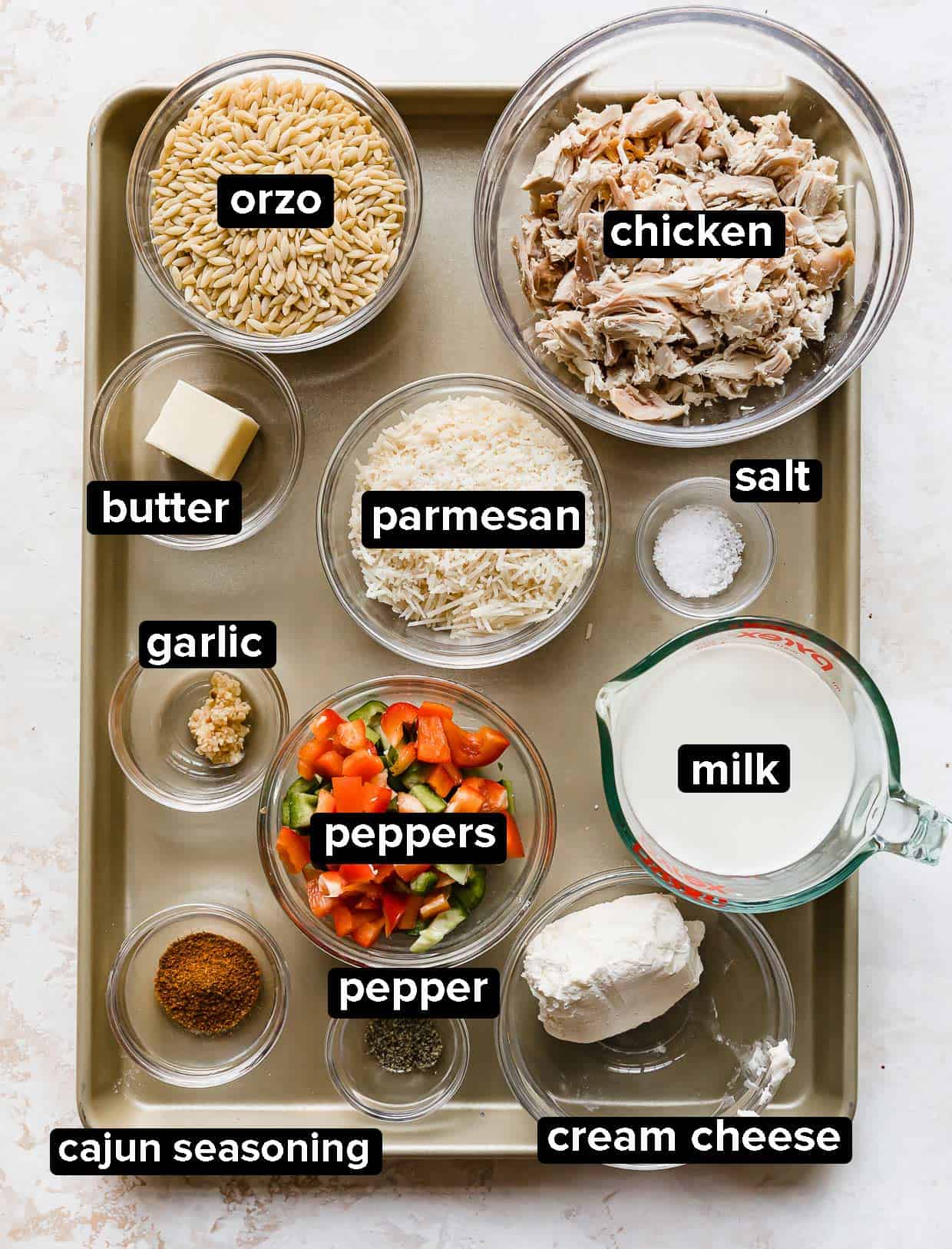 Cajun Chicken Orzo ingredients portioned into glass bowls on a baking sheet.