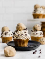 A chocolate chip cookie dough cupcake topped with cookie dough frosting and a ball of edible cookie dough.