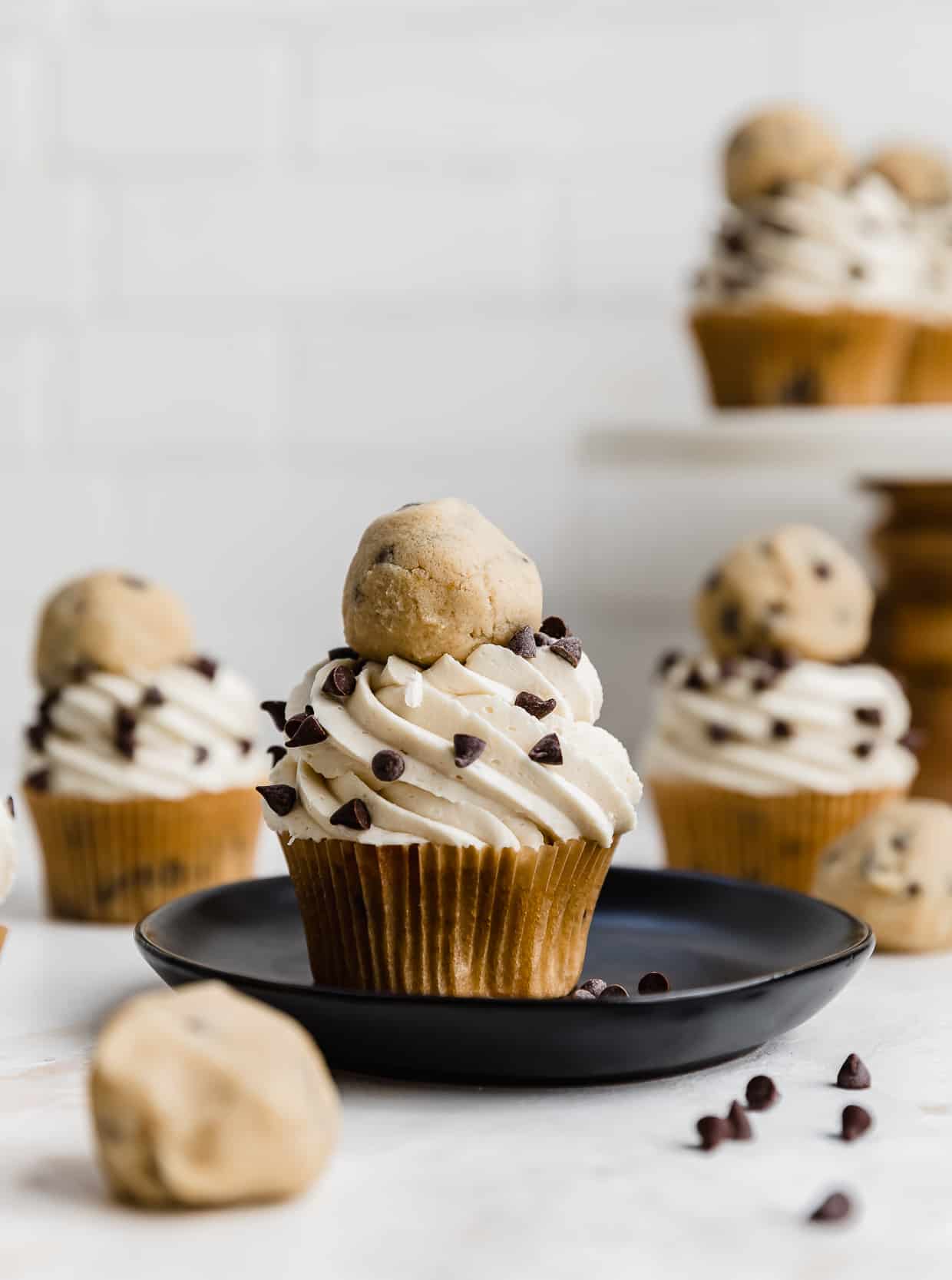 A chocolate chip cookie dough cupcake topped with cookie dough frosting and a ball of edible cookie dough.