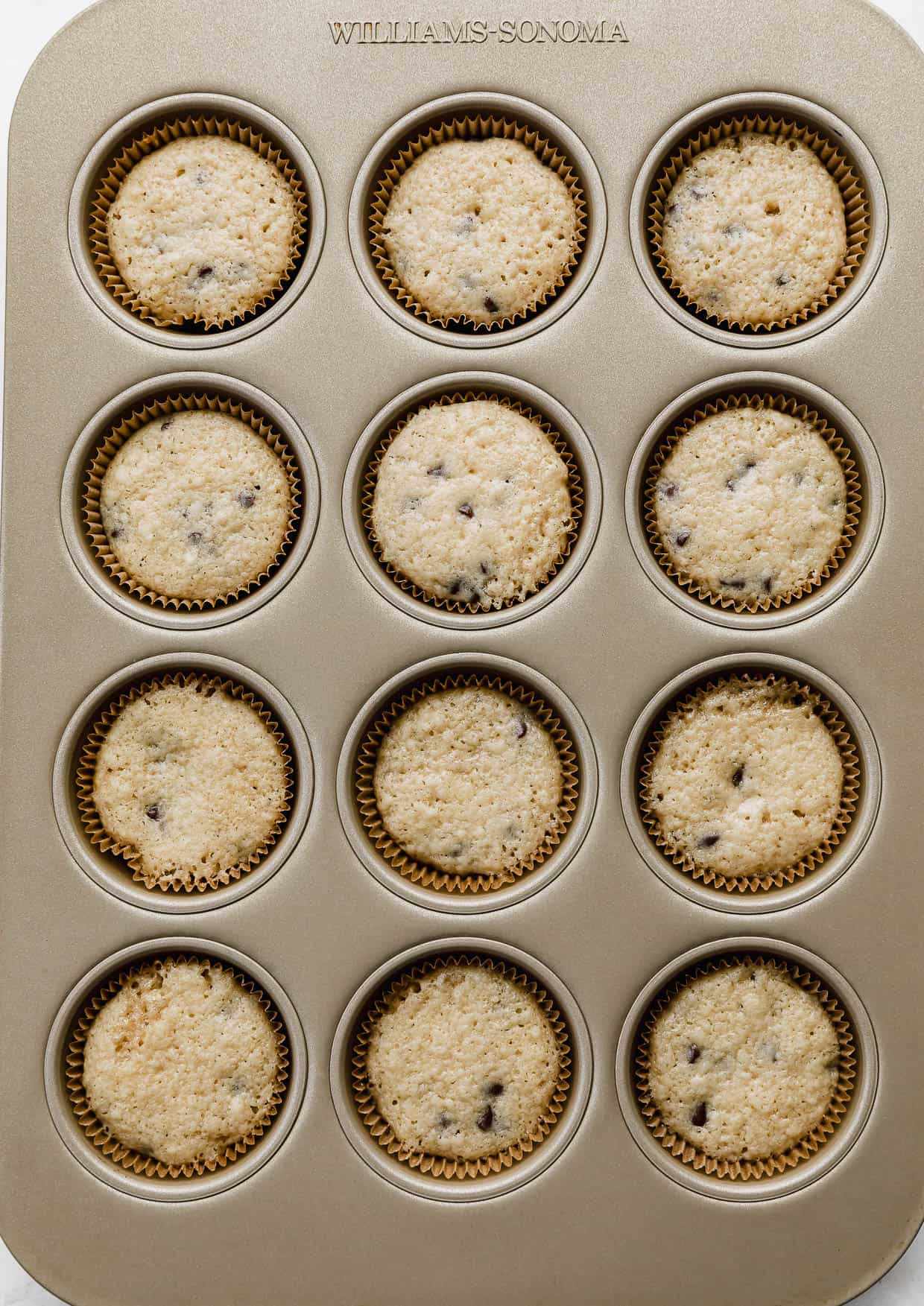 Chocolate Chip Cookie Dough Cupcakes in a gold muffin tin.