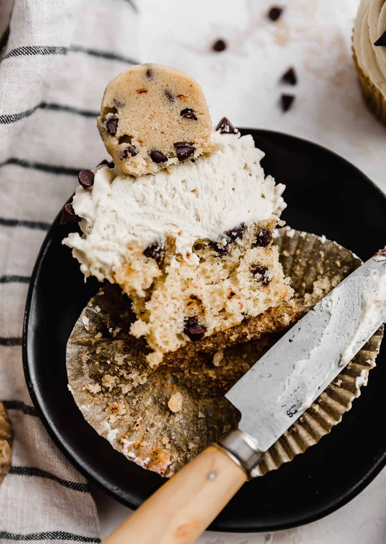 A Cookie Dough Cupcake cut in half showing, on a black plate.
