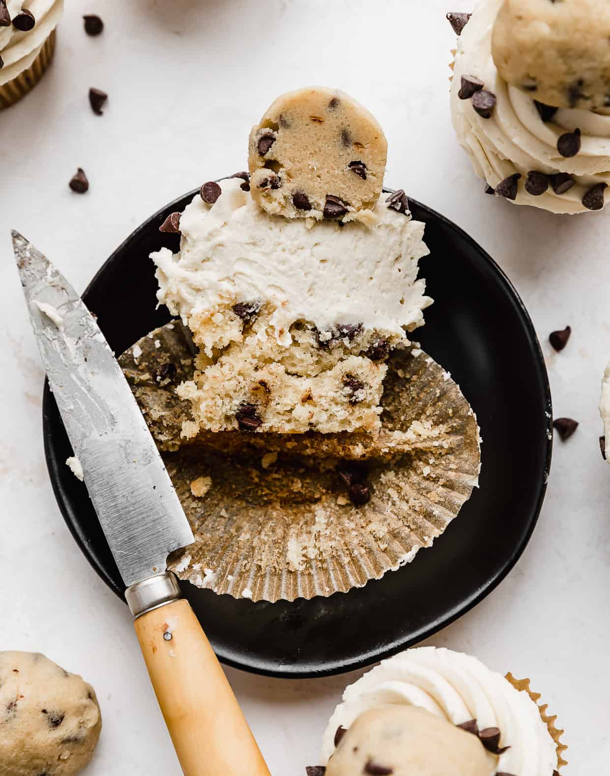 A Cookie Dough Cupcake sliced in half on a black plate.